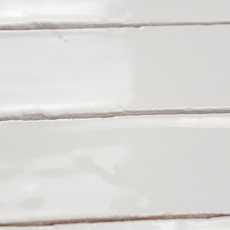Rectangular glazed white tile with brown grout joints, arranged in horizontal rows on a glossy wall.