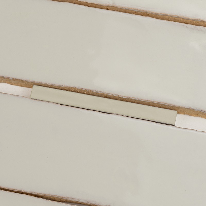 Rechthoekige witte geglazuurde tegel, horizontaal geplaatst; zichtbare beige voegen en een smalle beige afstandhouder tussen tegels, achtergrond glanzend wit.