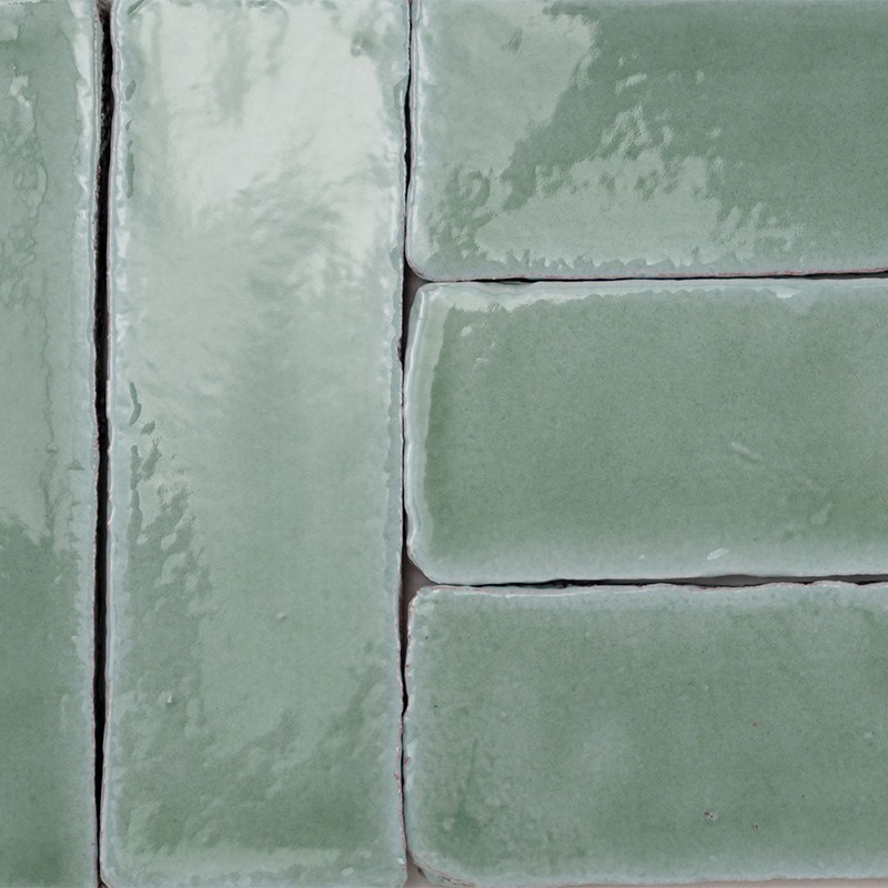 Green glazed rectangular tiles; context: placed in a staggered pattern with dark joints and a glossy surface that reflects light.