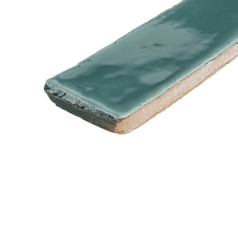 Smalle turquoise geglazuurde keramische tegelstrook met licht afgeronde rand en zichtbare onbehandelde onderzijde, geplaatst op een witte achtergrond.