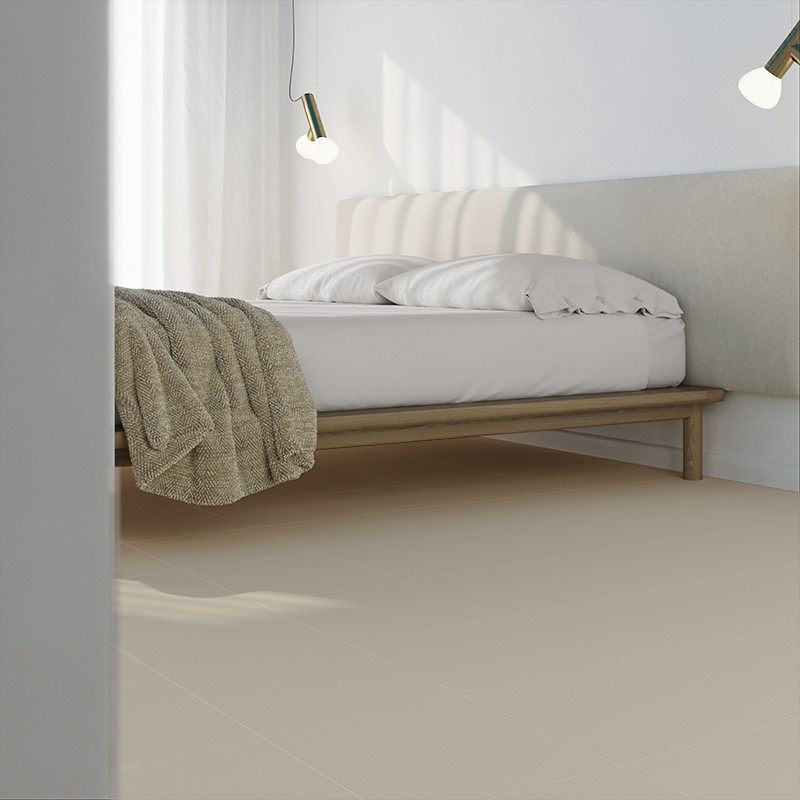 Beige tegelvloer in moderne slaapkamer, laag houten bed met wit dekbed en gebreide deken, gestoffeerd hoofdeinde, twee hanglampen en zacht daglicht.