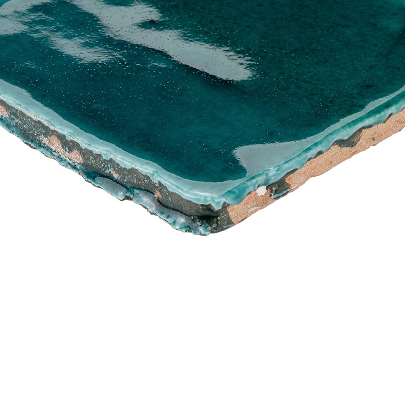 Blue-green glazed tile, visible corner showing layers of glaze and exposed ceramic body; shiny surface with veins and reflections, white background.