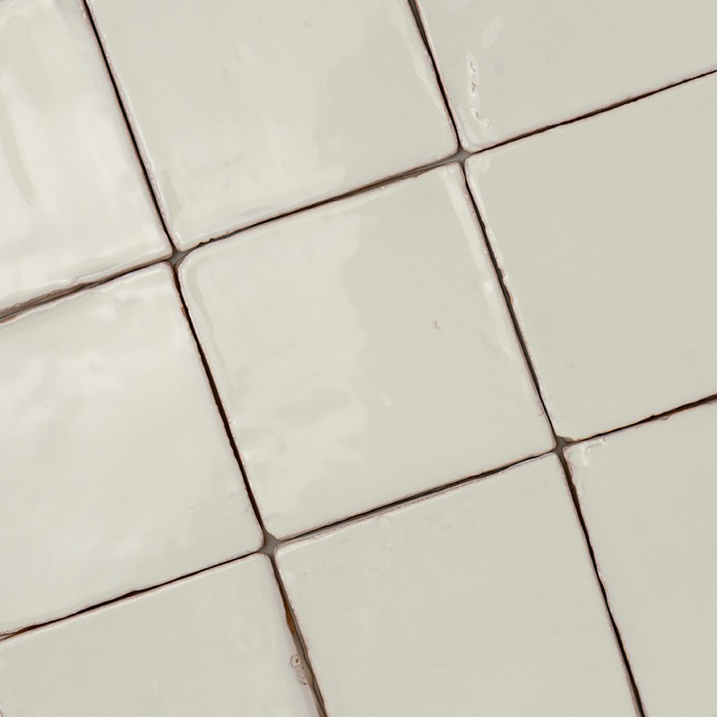 Cream square ceramic tiles with a glossy finish; thin, dark joints form a diagonal pattern, uniform surface, possibly for wall or countertop.