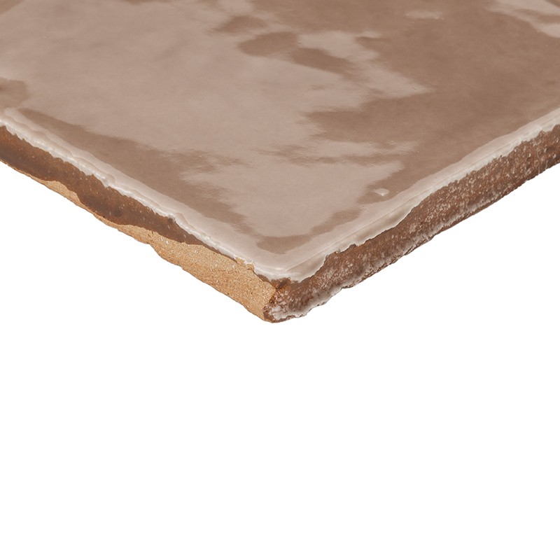 Carrelage carré brun glaçuré, coin mis en avant montrant bord coupé et dos argileux non émaillé; surface brillante reflétant la lumière, fond blanc.