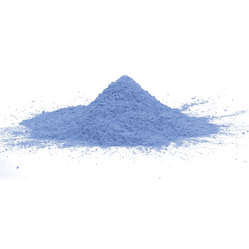 Un monticule conique de poudre bleu clair repose sur une surface blanche, s'étalant légèrement vers l'extérieur à la base.