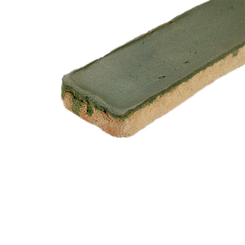 Smalle rechthoekige tegel met glanzende donkergroene bovenlaag en ruwe beige zijde, lichte druppelvlekken langs rand; ligt diagonaal gepositioneerd op effen witte achtergrond.