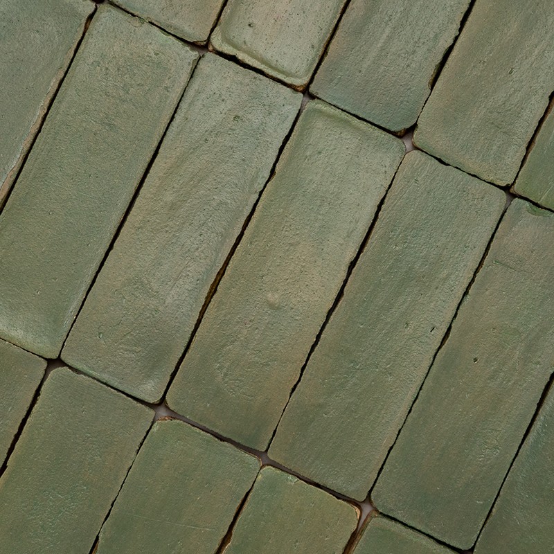 Groene rechthoekige tegels, licht geglazuurd en licht gesleten; in diagonale, overlappende rijen met smalle voegjes tussen tegels.