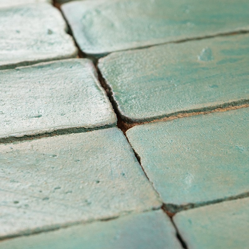 Carrelage turquoise en grands carreaux rectangulaires, surface émaillée et légèrement usée; joints sombres et profonds, texture rugueuse et nuances verdâtres.