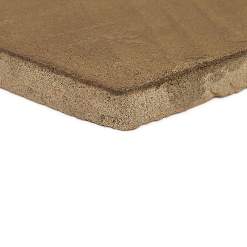 Rectangular ceramic tile with irregular edge and rough beige-brown surface; resting on a white background, close-up view showing edge and thickness.
