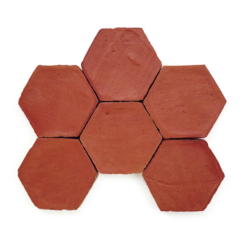 Sechseckige, rötlich-braune Terrakotta-Fliese mit leicht rauer Oberfläche, minimal abgenutzte Kanten, isoliert auf weißem Hintergrund.