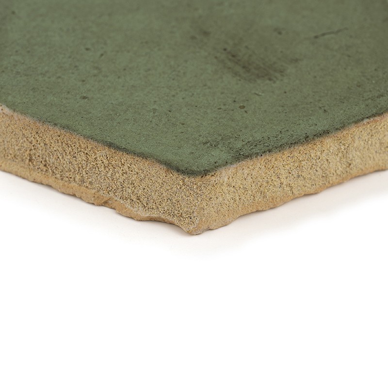 Carreau rectangulaire à surface émaillée vert pâle; tranche épaisse poreuse beige visible, angle biseauté; posé sur fond blanc neutre.