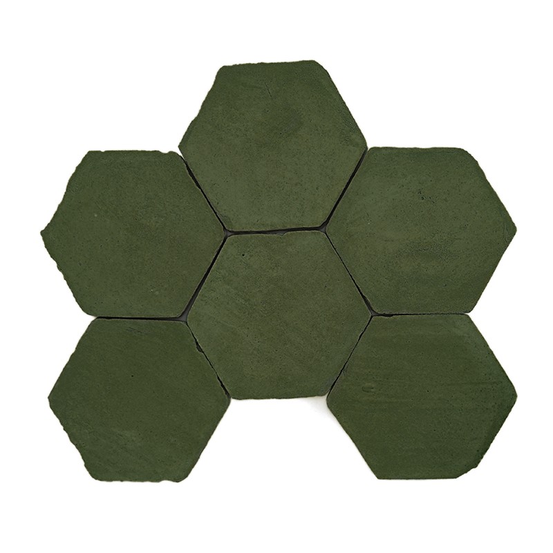 Hexagonale, olivgrüne Fliese mit leicht strukturierter Oberfläche, abgerundeten Kanten und kleinen dunklen Flecken, freistehend auf weißem Hintergrund.