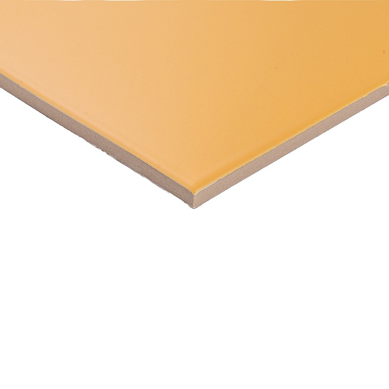 Fliese: dünne, rechteckige Ecke mit glänzender orange-gelber Oberfläche, sichtbare beige Kernschicht, scharfe Kante, freigestellt vor weißem Hintergrund.