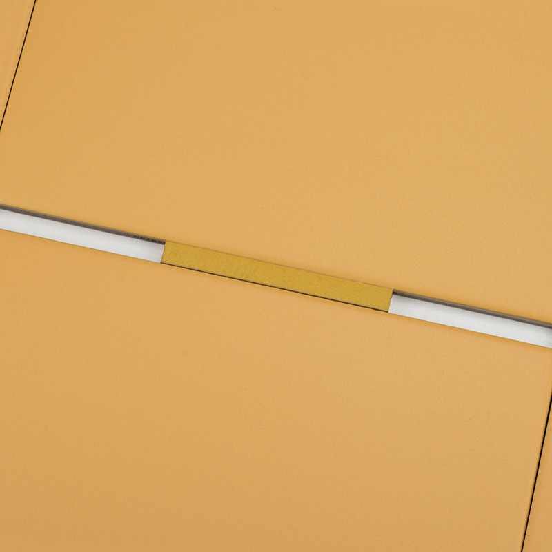 Square mustard-colored tile with white grout and a gold strip at the joint; surroundings: other similar tiles aligned forming a geometric pattern.