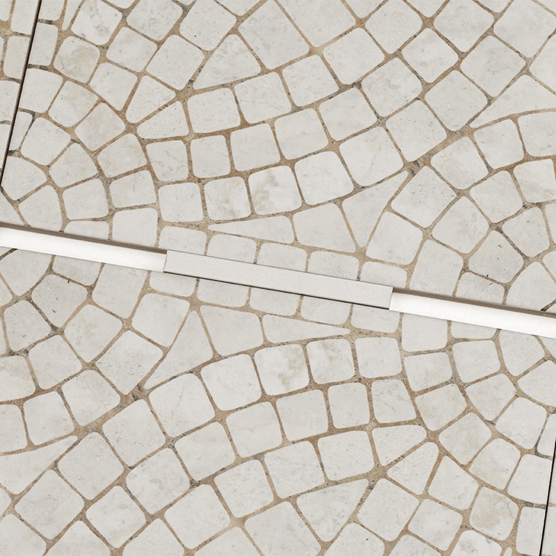 Azulejo mosaico blanco de pequeñas piezas cuadradas formando arcos concéntricos; juntas marrones; una tira lineal blanca y estrecha cruza diagonalmente el suelo.