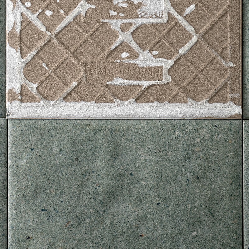 Brown tile with a diamond relief pattern and grout residue; the text "MADE IN SPAIN" is displayed. Below, a plain green tile with visible grout lines is shown.