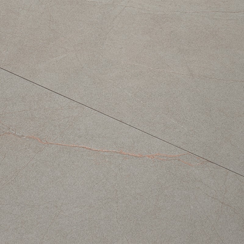 Carrelage gris clair texturé avec une fine ligne noire diagonale et une veine rouge pâle sinueuse traversant la surface; plan horizontal, aspect pierre légèrement fissuré.