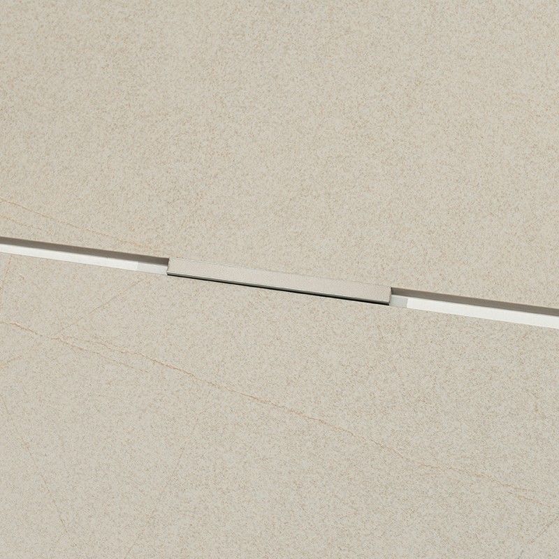 Matte beige tile with central joint and rectangular cap joining two pieces; fine texture with subtle veins, clean and minimalist environment.