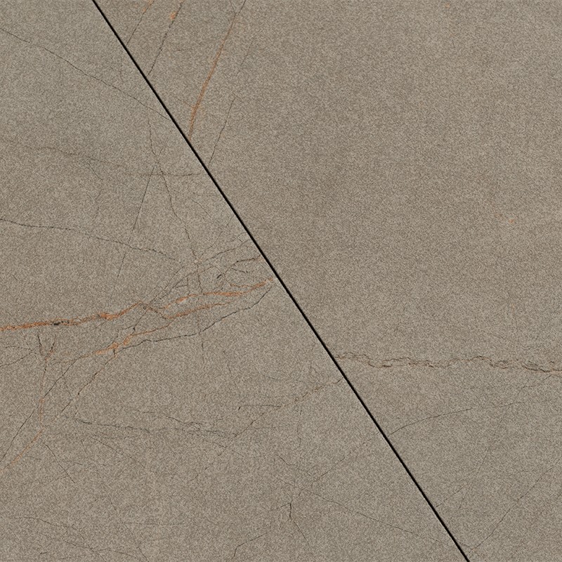 Grayish-brown tile with fine reddish veining and surface cracks; black diagonal joint dividing it, matte texture and stone appearance on a floor or wall covering.