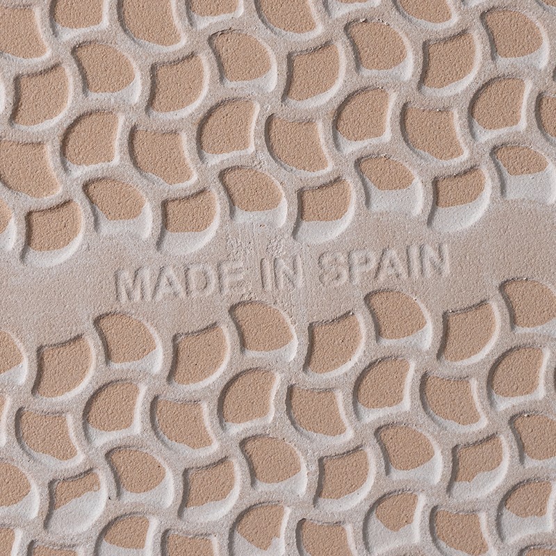 Semelle de chaussure en caoutchouc beige, motif répété de cellules arrondies; inscription en relief au centre: "MADE IN SPAIN".