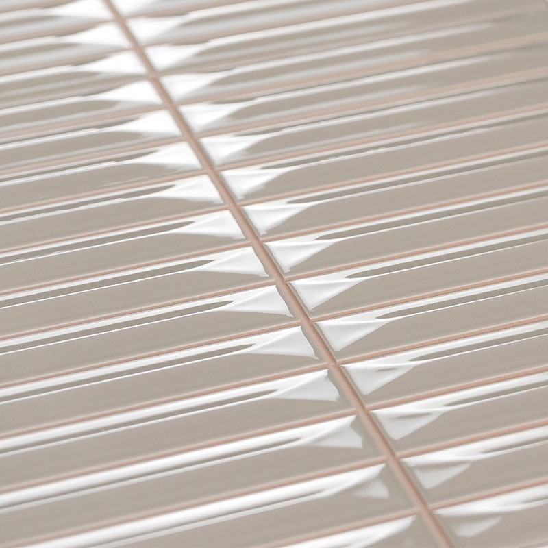 Carrelage rectangulaire céramique crème, relief biseauté et finition brillante; joints rosés clairs en croisillon, posé en grille, reflets lumineux suggérant un mur intérieur moderne.