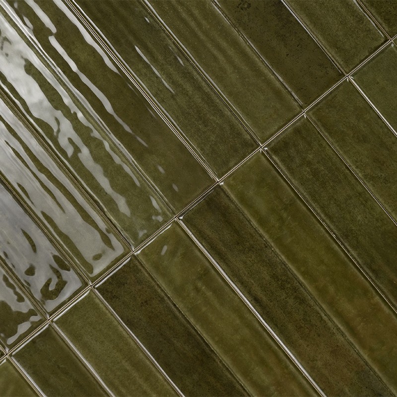 Donkergroene geglazuurde rechthoekige wandtegels met zichtbare voegnaden, diagonaal gelegd; glanzend oppervlak toont reflecties en subtiele kleurvariaties.