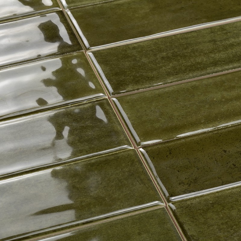 Rechthoekige, geglazuurde groene tegels met smalle witte voegen; glanzende oppervlakreflecties en lichte kleurvariaties, geplaatst in een regelmatig raster.