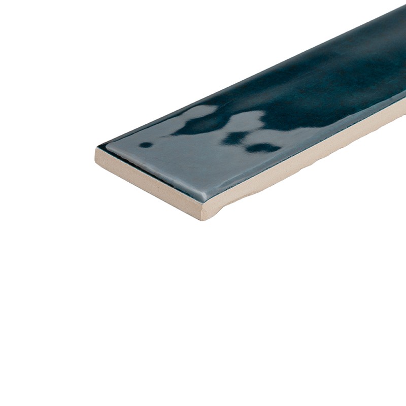 Carreau rectangulaire étroit émaillé bleu profond, surface brillante avec reflets, bordure claire montrant l'épaisseur de la tuile, présenté isolé sur fond blanc.