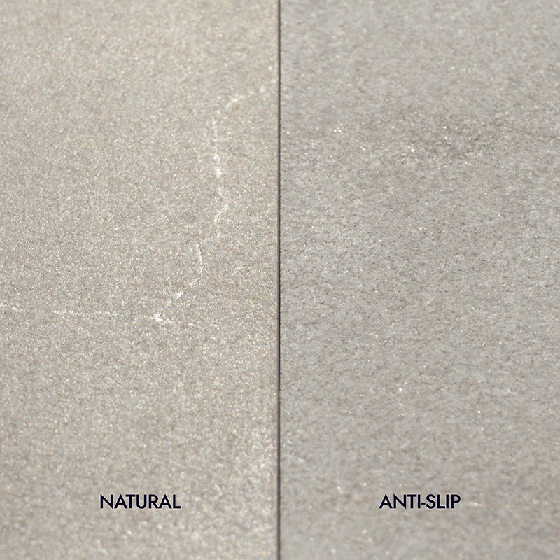 Carrelage: deux dalles adjacentes séparées par un joint vertical; surface granuleuse gris-beige, gauche marquée "NATURAL", droite marquée "ANTI-SLIP".