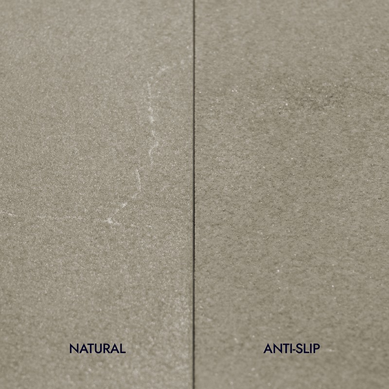 Vertically divided tile: smooth left side labeled NATURAL, textured non-slip right side labeled ANTI-SLIP; thin central joint.
