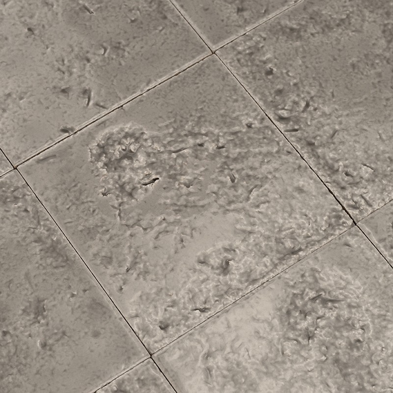 Square ceramic tile, rough and mottled surface, thin joints forming a diagonal pattern, light gray color with irregular wear; environment: other similar adjacent tiles.