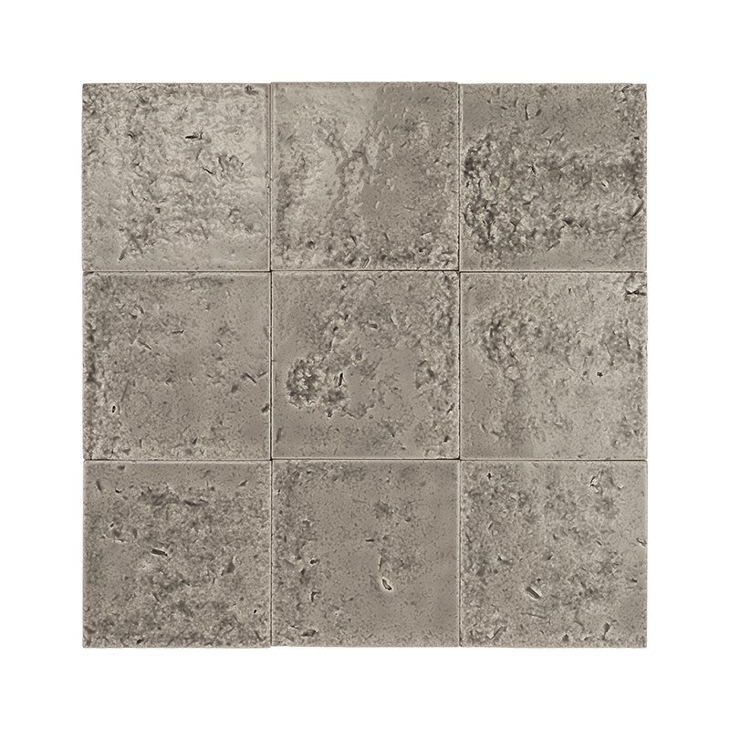 Azulejo quadrado bege-acinzentado com superfície áspera e irregular, marcas e pequenos sulcos, bordas levemente desgastadas; aparenta material cerâmico envelhecido.