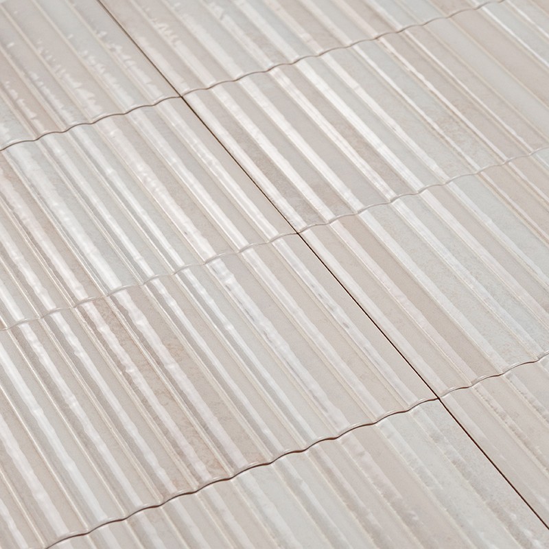 Teja cerámica acanalada beige en filas solapadas, formando una cubierta; superficies brillantes, juntas visibles y una grieta fina a lo largo de una unión.