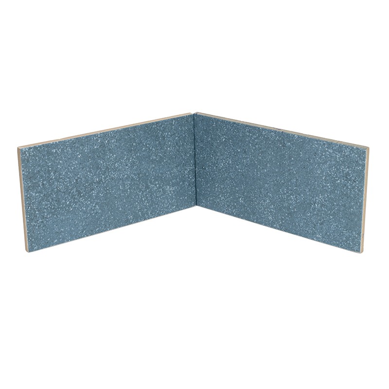 Azulejo rectangular azul grisáceo moteado con brillo, formado por dos piezas unidas en ángulo recto; bordes claros y fondo blanco neutro.