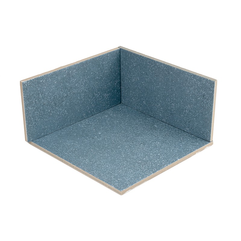Eckfliese in Blau mit körniger Oberfläche, zwei senkrechte Seiten und eine Bodenfläche bilden einen rechten Innenwinkel; beige Kanten, freigestellt vor weißem Hintergrund.