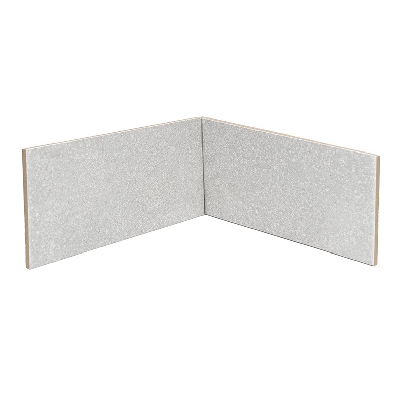 Carrelage d'angle gris clair à motif granité, deux carreaux rectangulaires assemblés formant un angle droit sur fond blanc.