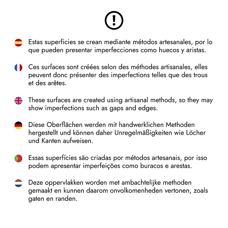 White plaque (tile) with an exclamation mark above and multilingual text warning of possible imperfections due to artisanal methods.  Full transcription: 🇪🇸 These surfaces are created using artisanal methods, so they may have imperfections such as gaps an