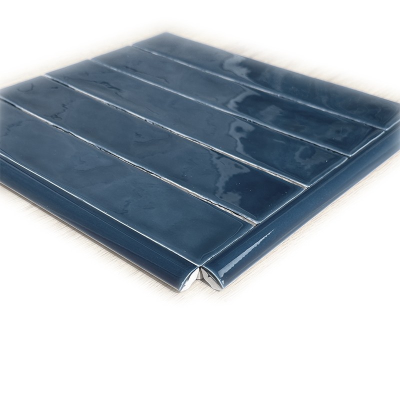 Carrelage métro bleu brillant, cinq lames empilées montrant angle biseauté, surface émaillée réfléchissante et joints fins sur fond blanc.