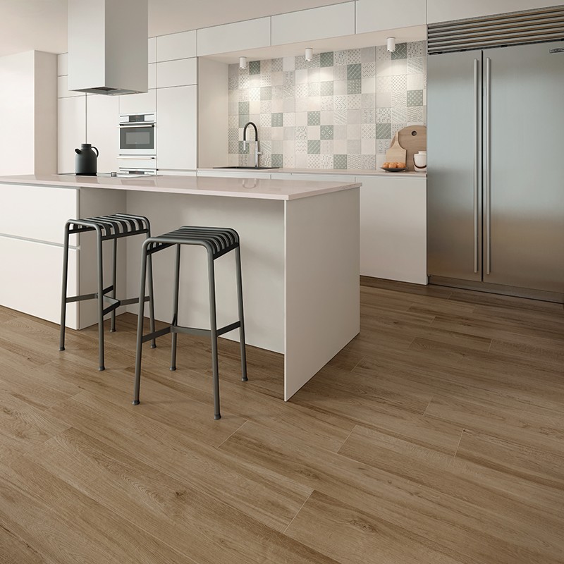 Quadratische, helle Wandfliesen in wechselnden dezenten geometrischen Mustern; moderne weiße Küche mit Insel, zwei schwarzen Barhockern, Edelstahlkühlschrank, Spüle und hellem Holzfußboden.