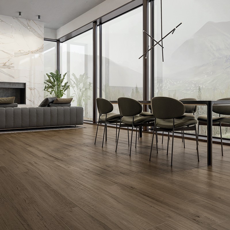 Revestimento cerâmico imitação madeira em tons médios; sala ampla com sofá cinza, mesa de jantar com cadeiras, grandes janelas panorâmicas e parede de mármore com lareira, vista para montanhas.