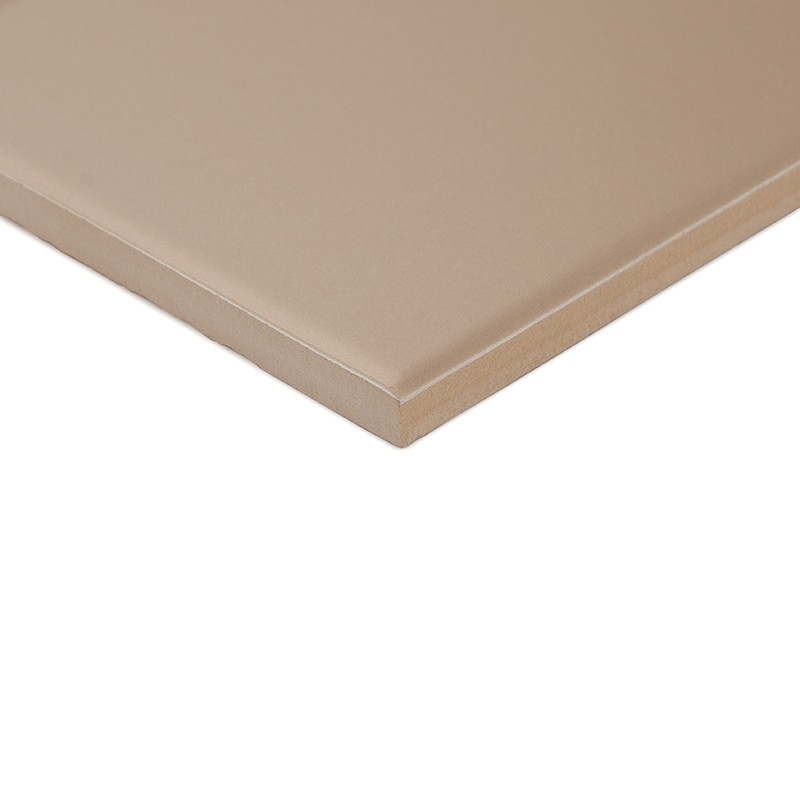 Azulejo rectangular beige con borde biselado y superficie lisa mate; mostrado aislado en ángulo sobre fondo blanco, enfatizando espesor y esquina.