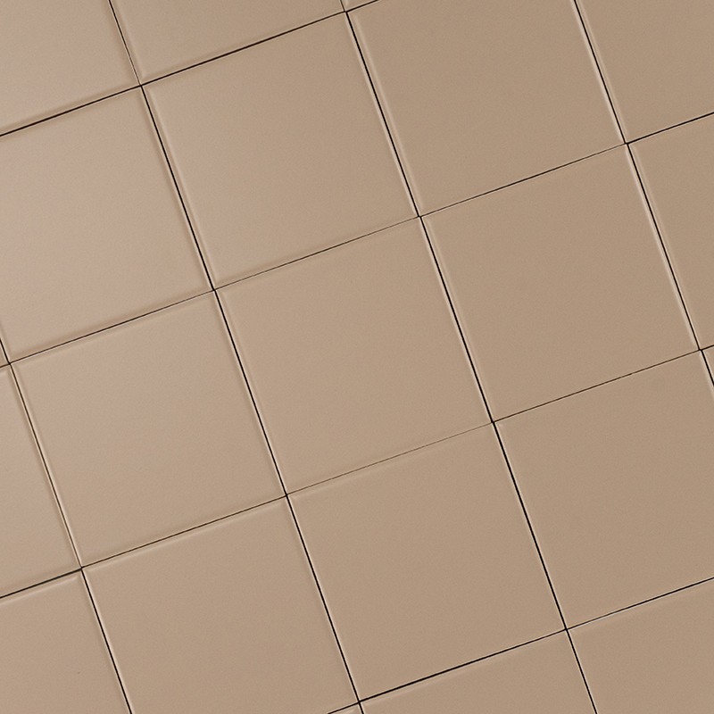 Azulejos cuadrados beige mate: patrón repetido de baldosas alineadas con juntas finas, formando una cuadrícula uniforme vista en ligera perspectiva diagonal.