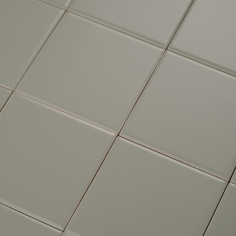 Carrelage blanc cassé, carreaux carrés brillants aux bords arrondis, joints fins gris clair; vue en plongée montrant plusieurs rangées et coins alignés.
