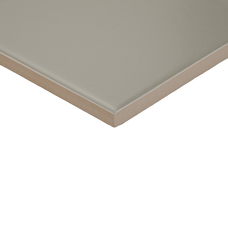 Fliese in hellem Grau mit mattem Finish; Eckansicht, sichtbare abgeschrägte Kante und dünnes Braun/Beige‑Profil, freigestellt vor weißem, neutralem Hintergrund.