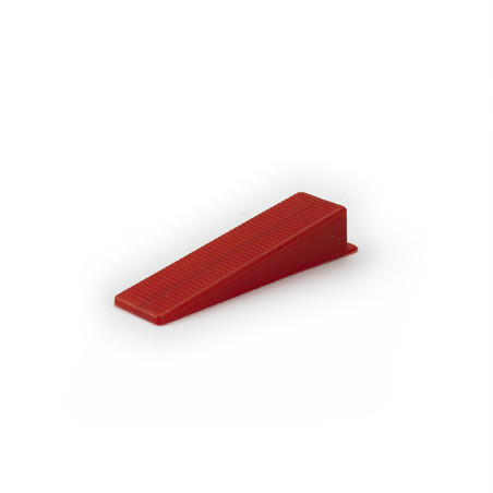 Auf einem schlichten weißen Hintergrund liegt ein kleiner, roter Plastikkeil mit geriffelter Struktur.