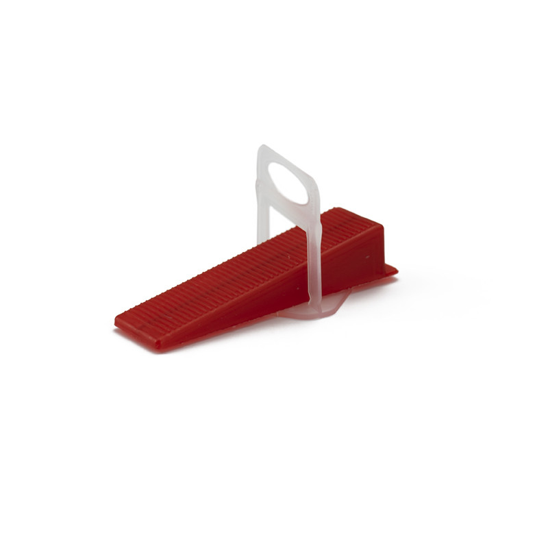 Auf einem schlichten weißen Hintergrund liegt ein kleiner, roter Plastikkeil mit geriffelter Struktur.