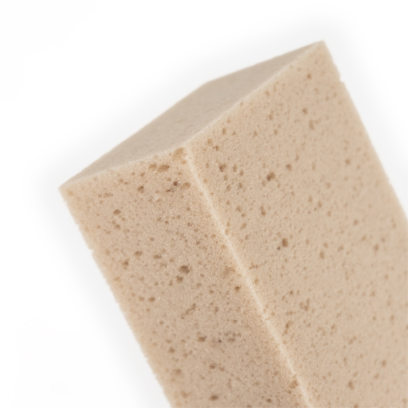 Een beige, rechthoekige spons met een poreuze textuur bevindt zich tegen een effen witte achtergrond.