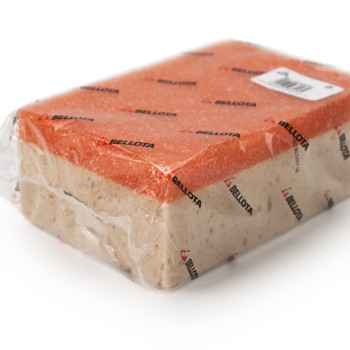 Een rechthoekige schoonmaakspons verpakt in doorzichtig plastic met rode en beige zijkanten, bedekt met de herhaalde tekst `BELL