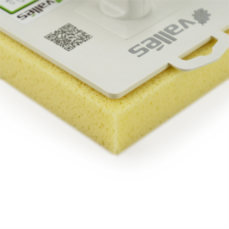 Une éponge jaune avec un manche en plastique blanc est exposée sur une surface blanche et propre. La surface comporte un code QR