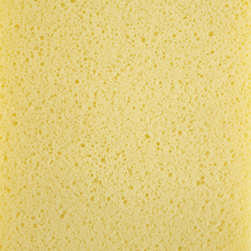 Une texture éponge jaune et poreuse avec de petits trous répartis uniformément sur la surface, remplissant tout le cadre.
